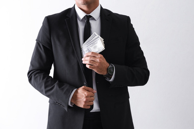 Man with bribe money on light background, closeup