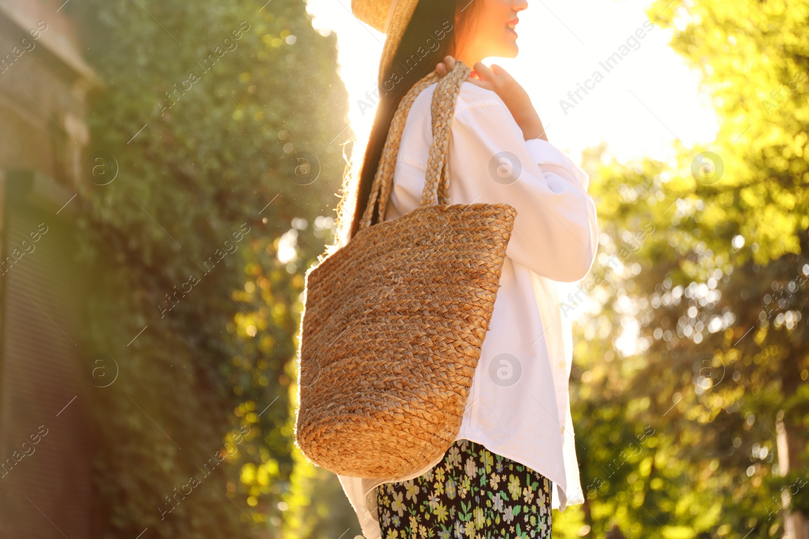 Photo of Young woman with stylish straw bag in park, closeup