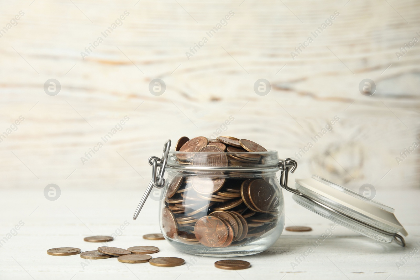 Photo of Glass jar with coins on white wooden table