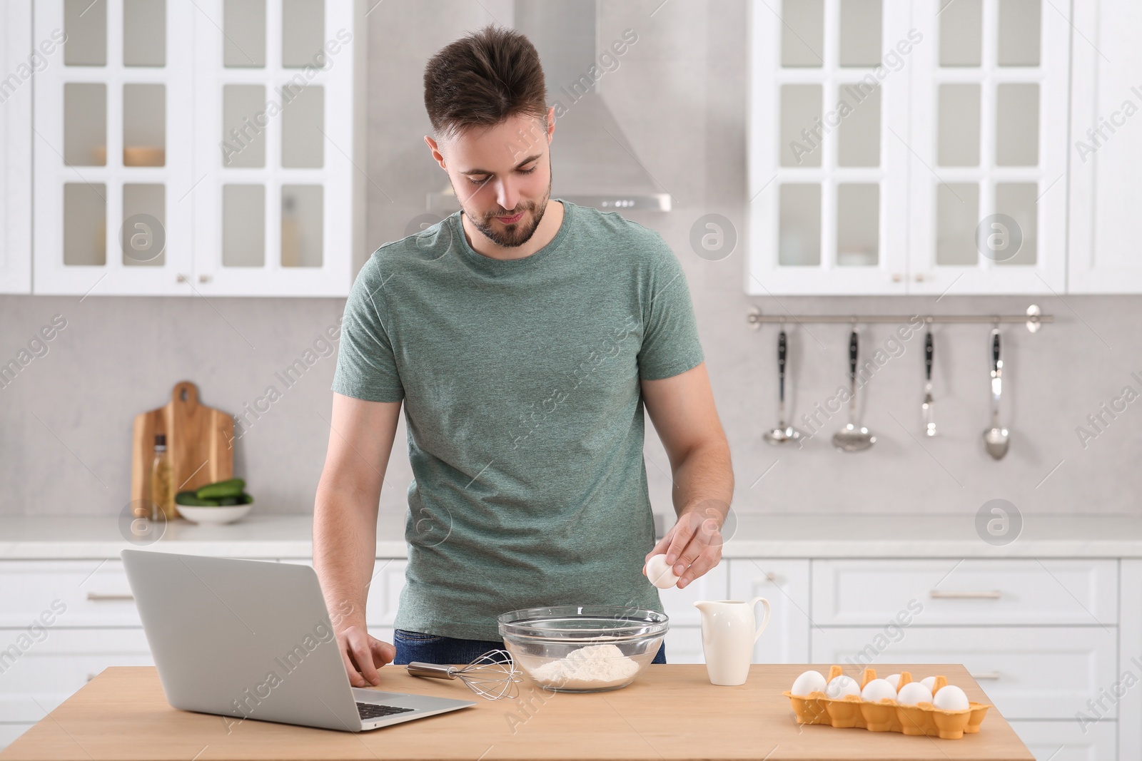 Photo of Man learning to cook with online video at table in kitchen. Time for hobby