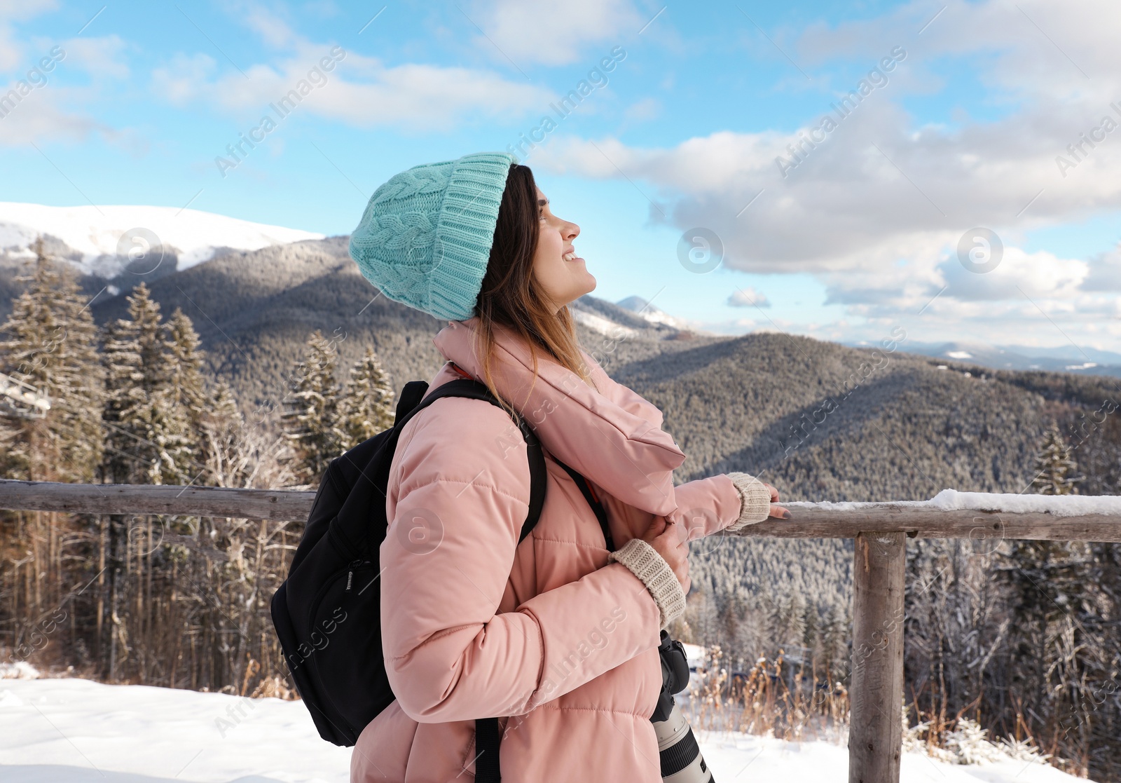 Photo of Young woman with backpack and camera enjoying mountain view during winter vacation