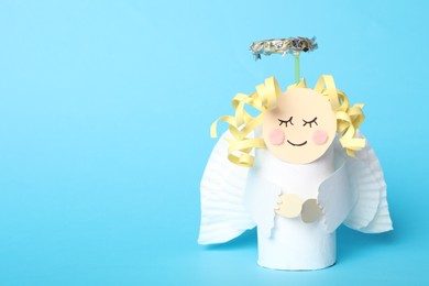 Photo of Toy angel made of toilet paper hub on light blue background. Space for text