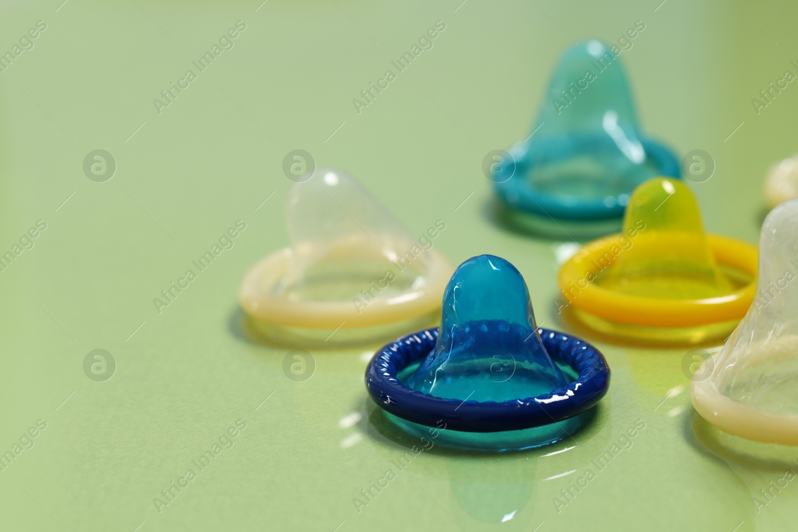 Photo of Condoms on light green background, closeup. Safe sex