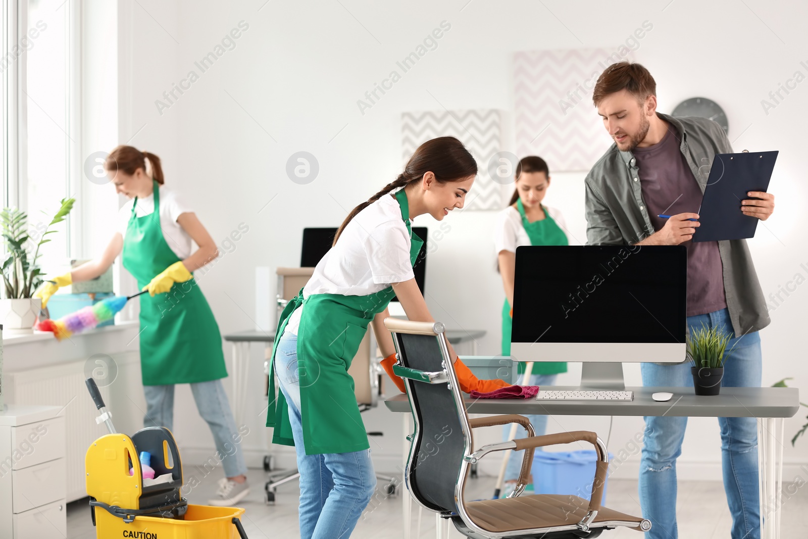 Photo of Team of professional janitors in uniform cleaning office