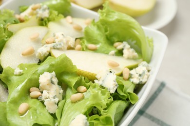 Photo of Fresh salad with pear slices in bowl, closeup