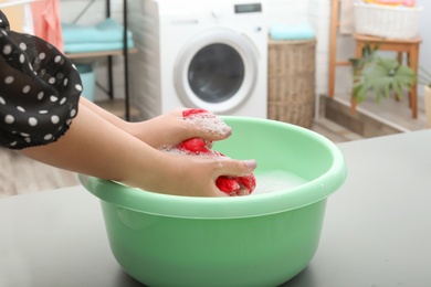 Photo of Woman washing color clothes in basin, closeup