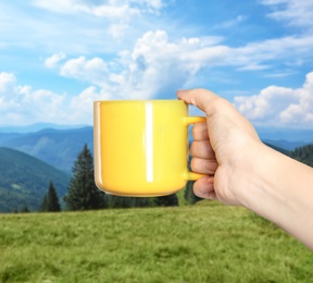 Image of Closeness to nature. Woman holding cup in mountains, closeup