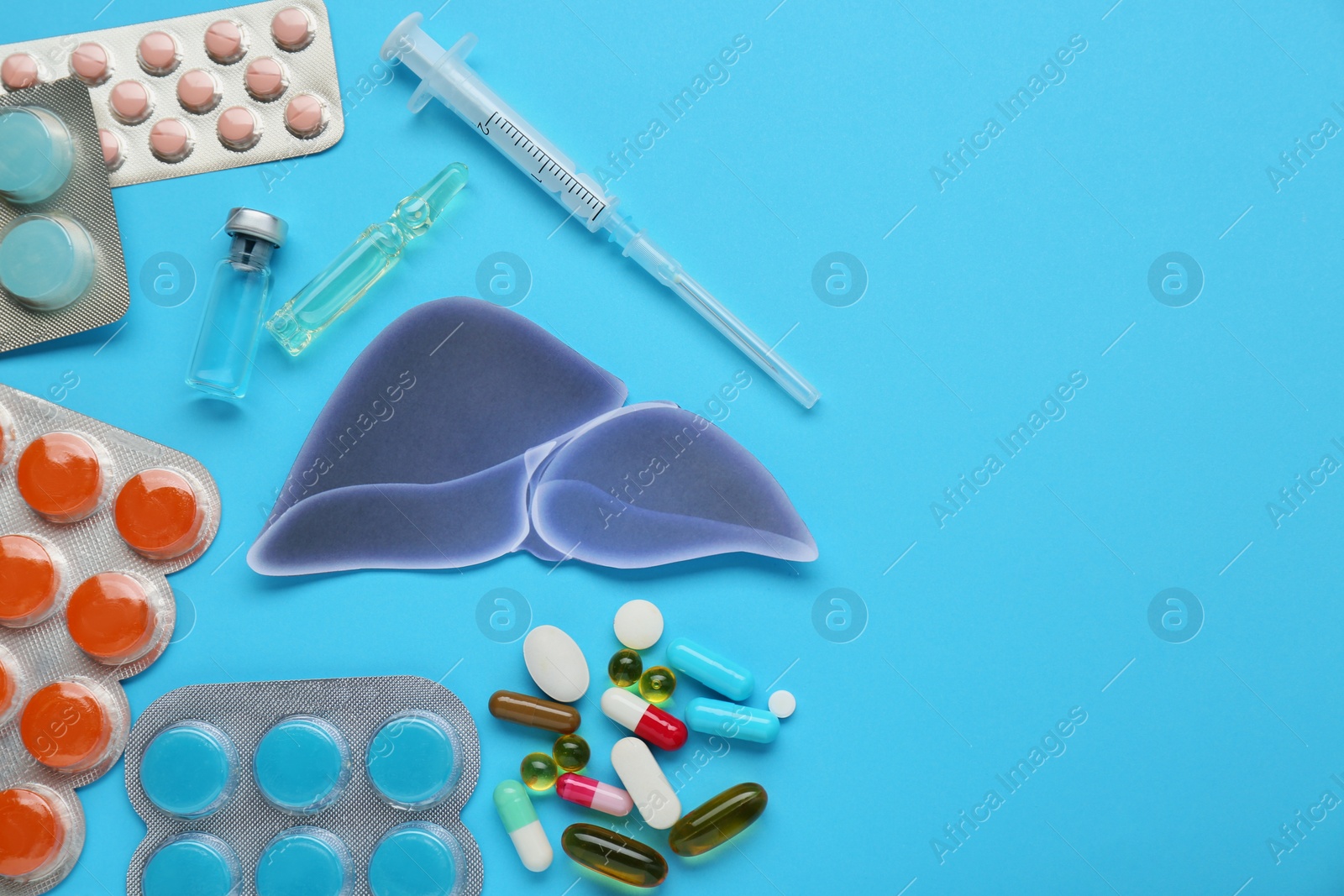 Photo of Paper liver and medical supplies on light blue background, flat lay with space for text. Hepatitis treatment