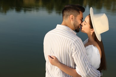 Photo of Romantic date. Beautiful couple kissing near lake