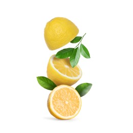Image of Cut fresh lemons with green leaves falling isolated on white