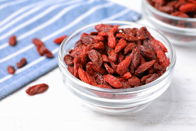 Photo of Dried goji berries on white wooden table, closeup