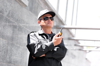 Photo of Male security guard using portable radio transmitter outdoors