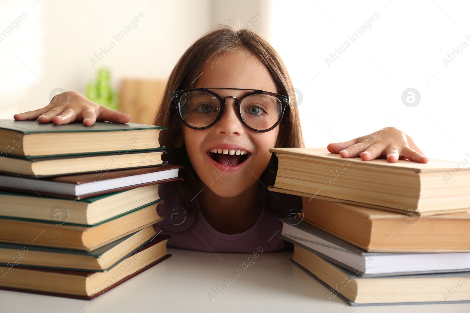 Photo of Emotional little girl at table with books. Doing homework