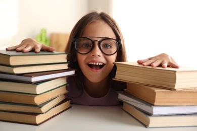 Emotional little girl at table with books. Doing homework