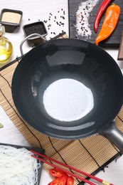 Photo of Wok, chopsticks and different products on white wooden table, above view