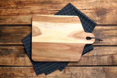 Photo of Cutting board and towel on wooden table, top view. Cooking utensil