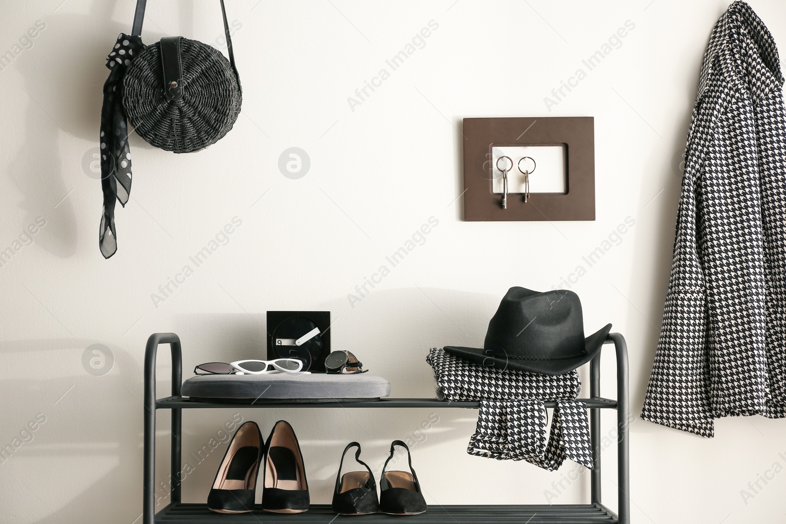 Photo of Black shelving unit with shoes and different accessories near white wall