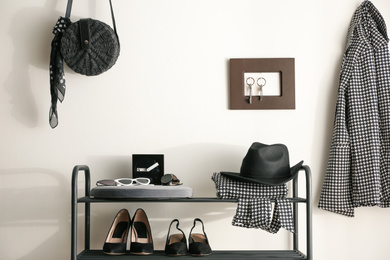 Photo of Black shelving unit with shoes and different accessories near white wall