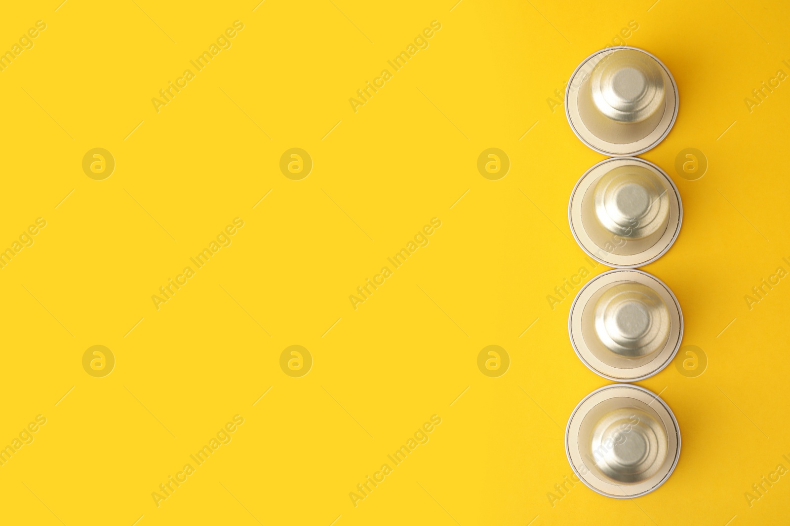 Photo of Many coffee capsules on yellow background, top view. Space for text