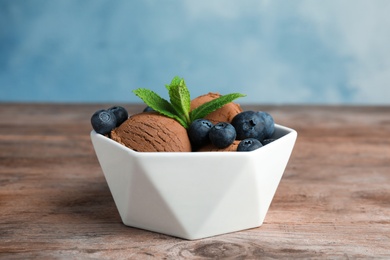 Photo of Bowl of chocolate ice cream and blueberries on wooden table. Space for text