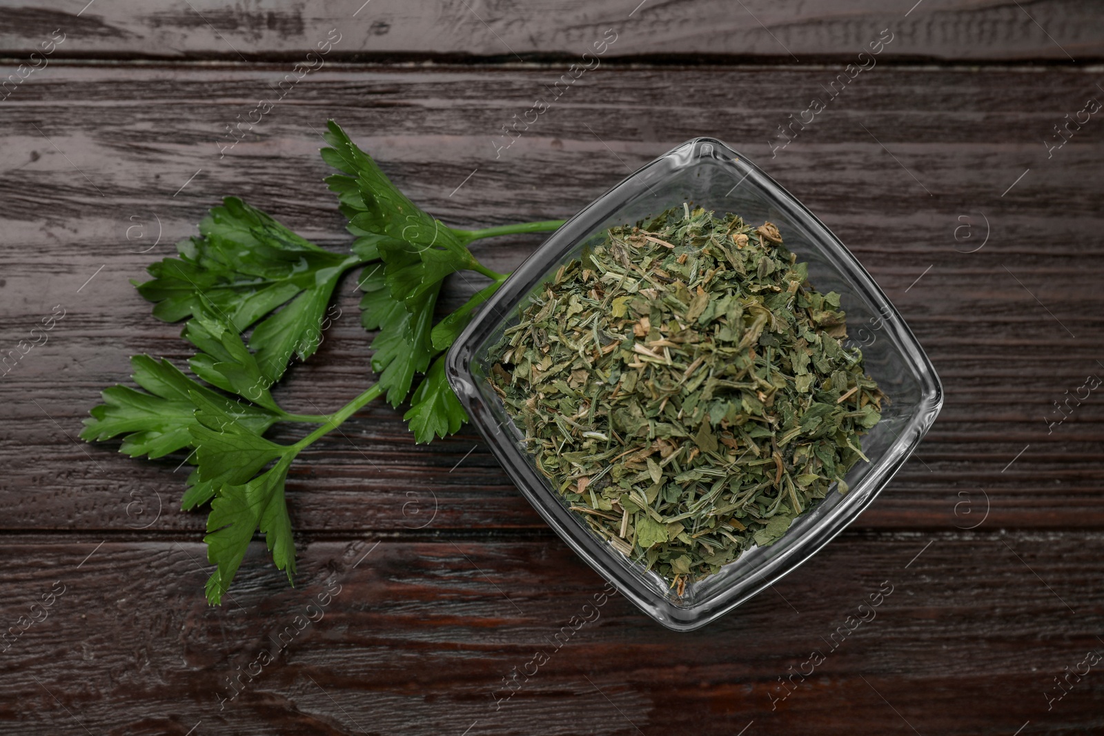 Photo of Dried aromatic parsley and fresh leaves on wooden table, flat lay