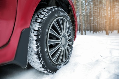 Modern car on snowy road in winter forest, closeup. Space for text