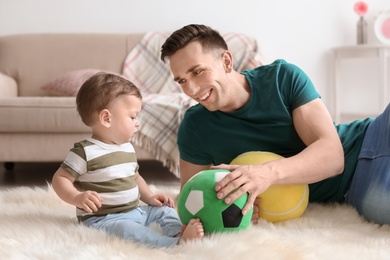 Photo of Young father with his cute little son at home