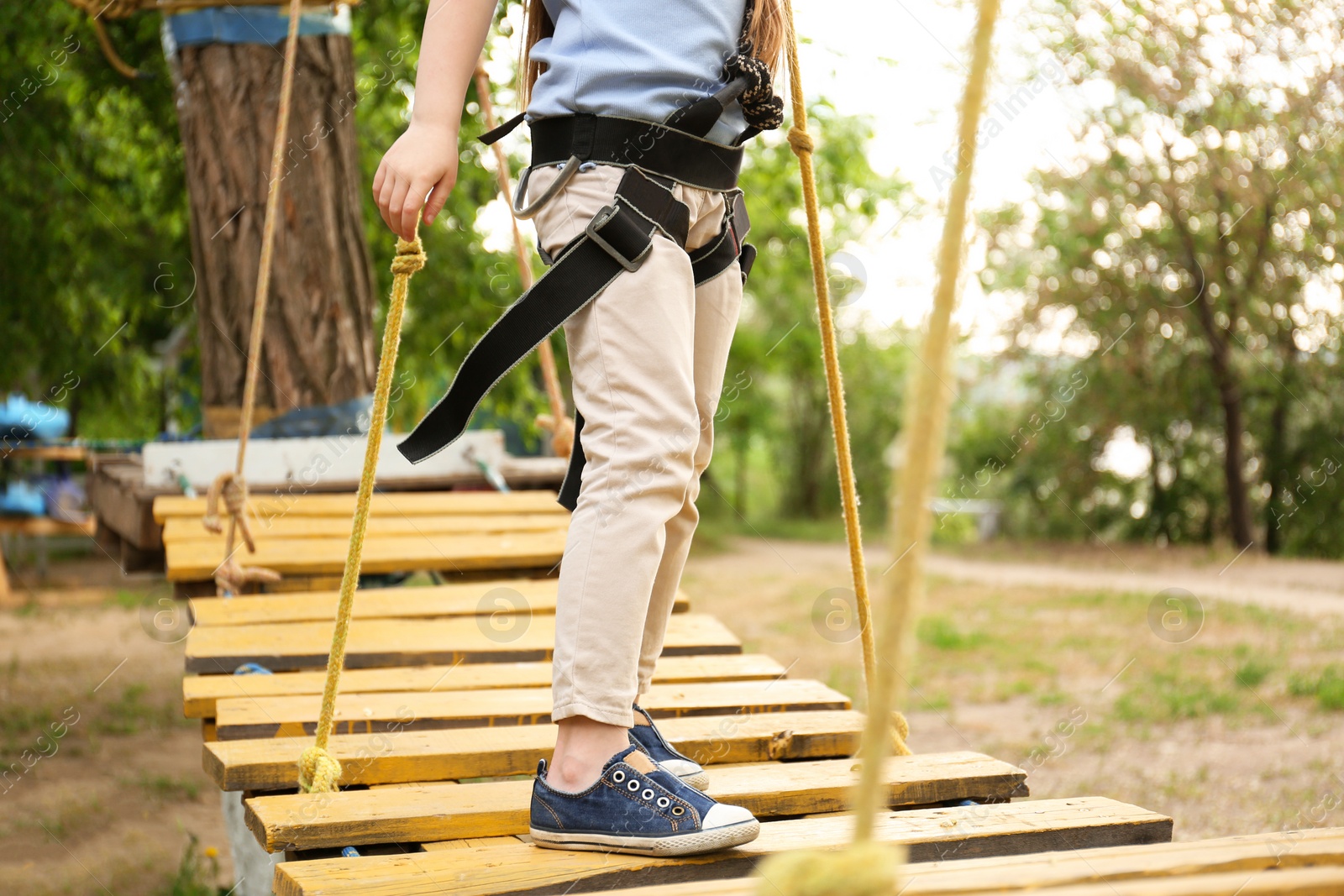 Photo of Little girl climbing in adventure park, closeup. Summer camp