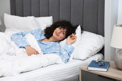 Beautiful young woman in stylish pyjama in bed at home