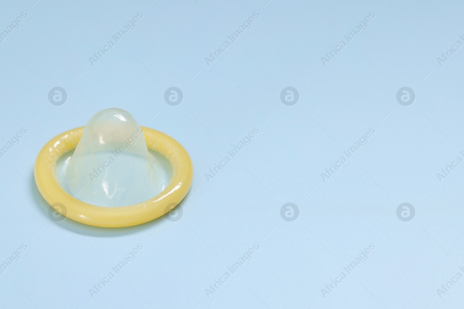 Photo of Condom on light blue background, space for text. Safe sex