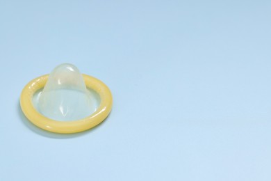 Photo of Condom on light blue background, space for text. Safe sex