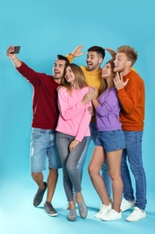 Happy young people taking selfie on blue background