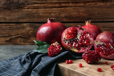 Ripe pomegranates on board against wooden background