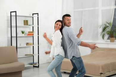 Happy young couple dancing together at home