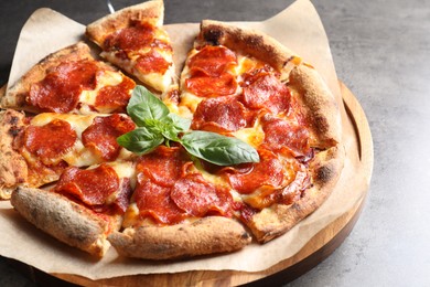 Photo of Tasty pepperoni pizza with basil on grey table