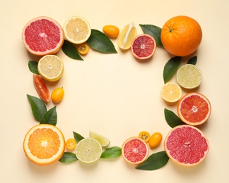 Photo of Frame of fresh juicy citrus fruits with green leaves on beige background, flat lay. Space for text