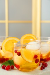 Photo of Delicious cocktails with orange, cranberries and ice balls on light grey marble table