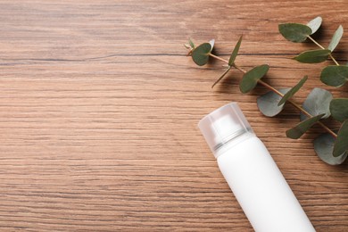 Photo of Dry shampoo spray and eucalyptus branches on wooden table, flat lay. Space for text