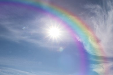 Image of Beautiful view of bright rainbow in blue sky on sunny day