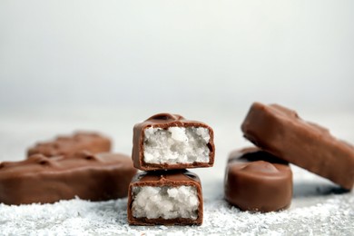 Photo of Delicious milk chocolate candy bars with coconut filling on grey table, closeup. Space for text