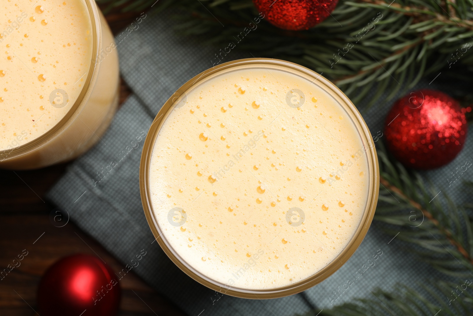 Photo of Glasses of delicious eggnog on wooden table, flat lay