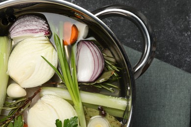 Different ingredients for cooking tasty bouillon in pot on black table, top view