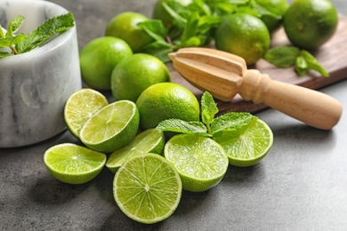 Photo of Ripe limes and mint on grey background. Refreshing beverage recipe