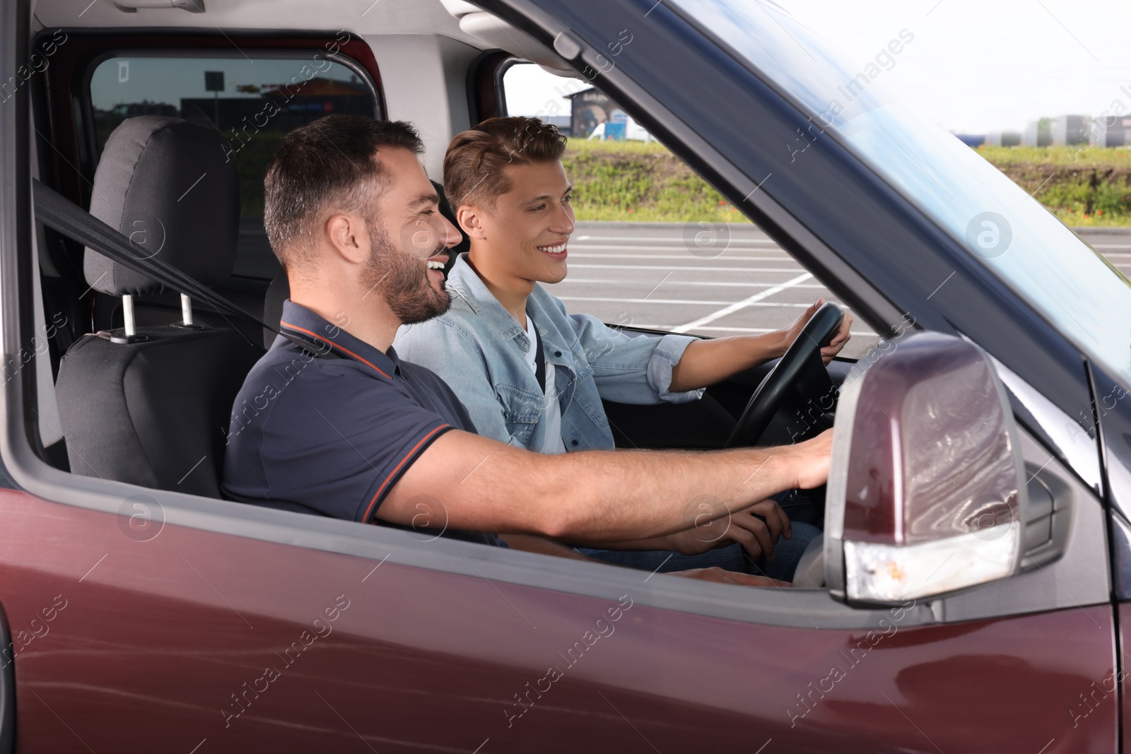 Photo of Driving school. Happy student during lesson with driving instructor in car at parking lot