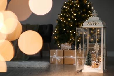 Vintage wooden lantern with beautiful Christmas composition surrounded by blurred festive lights indoors