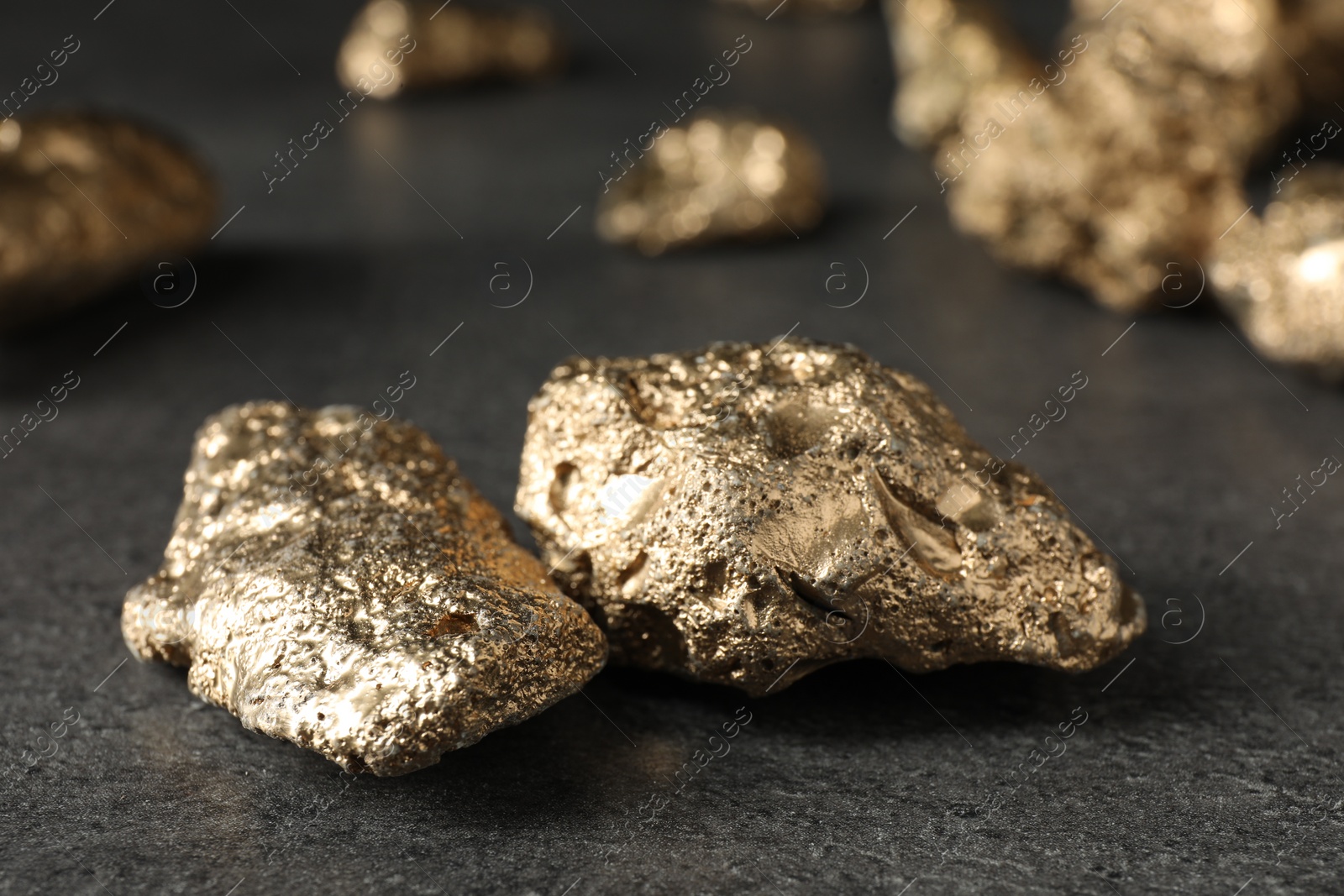 Photo of Shiny gold nuggets on grey textured surface, closeup