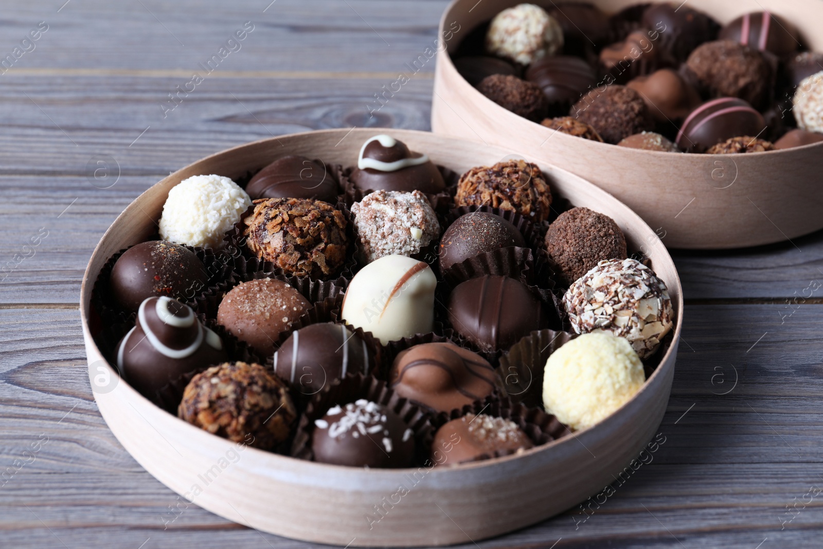 Photo of Boxes with tasty chocolate candies on wooden table, closeup