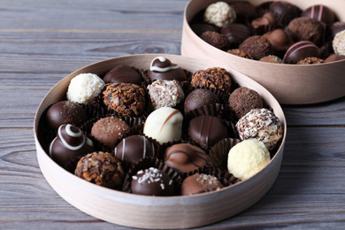 Boxes with tasty chocolate candies on wooden table, closeup