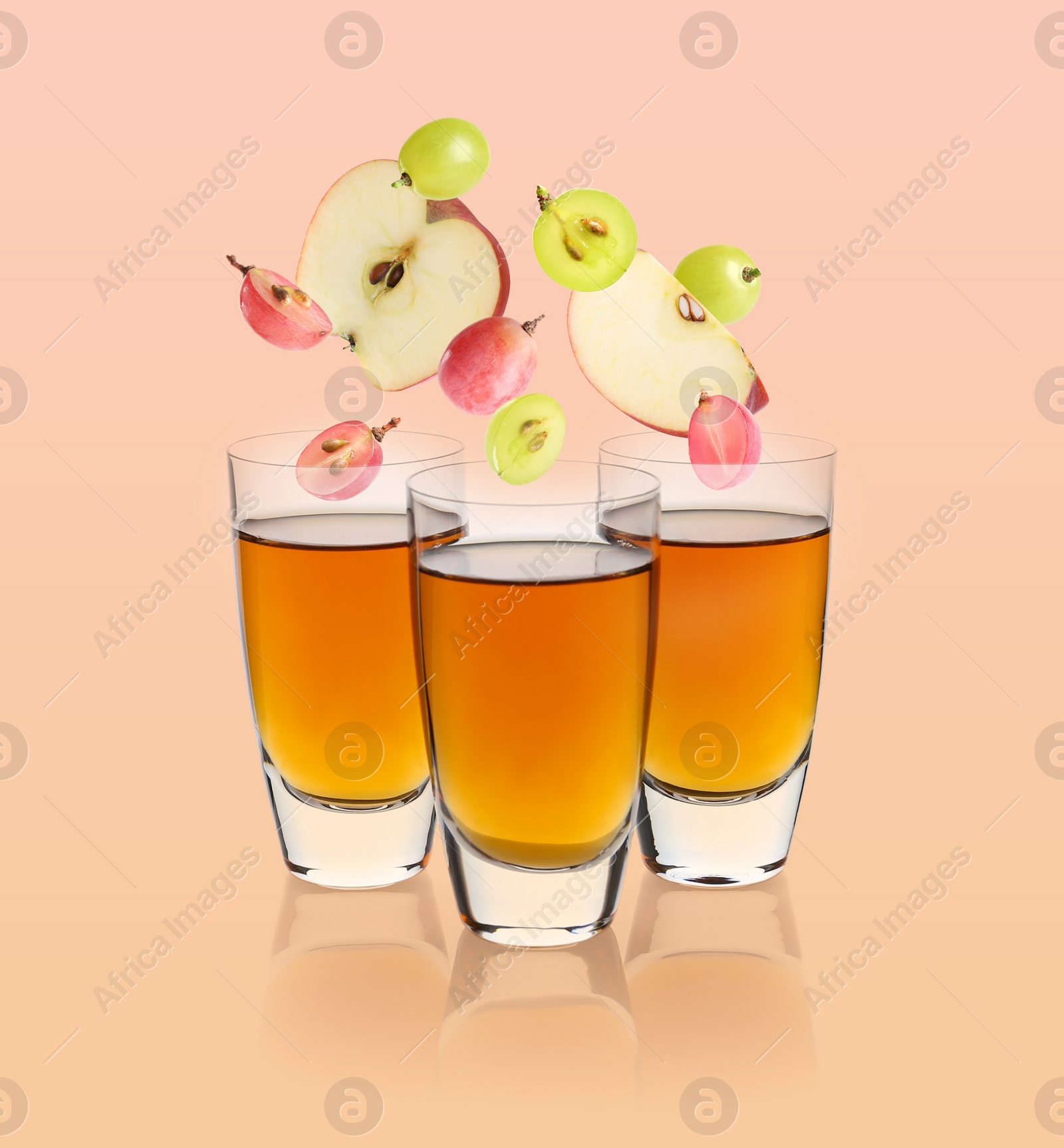 Image of Freshly made apple and grape nectar on beige background. Fruits falling into glasses