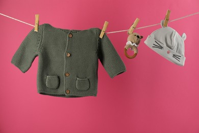 Photo of Baby clothes and accessories hanging on washing line against pink background